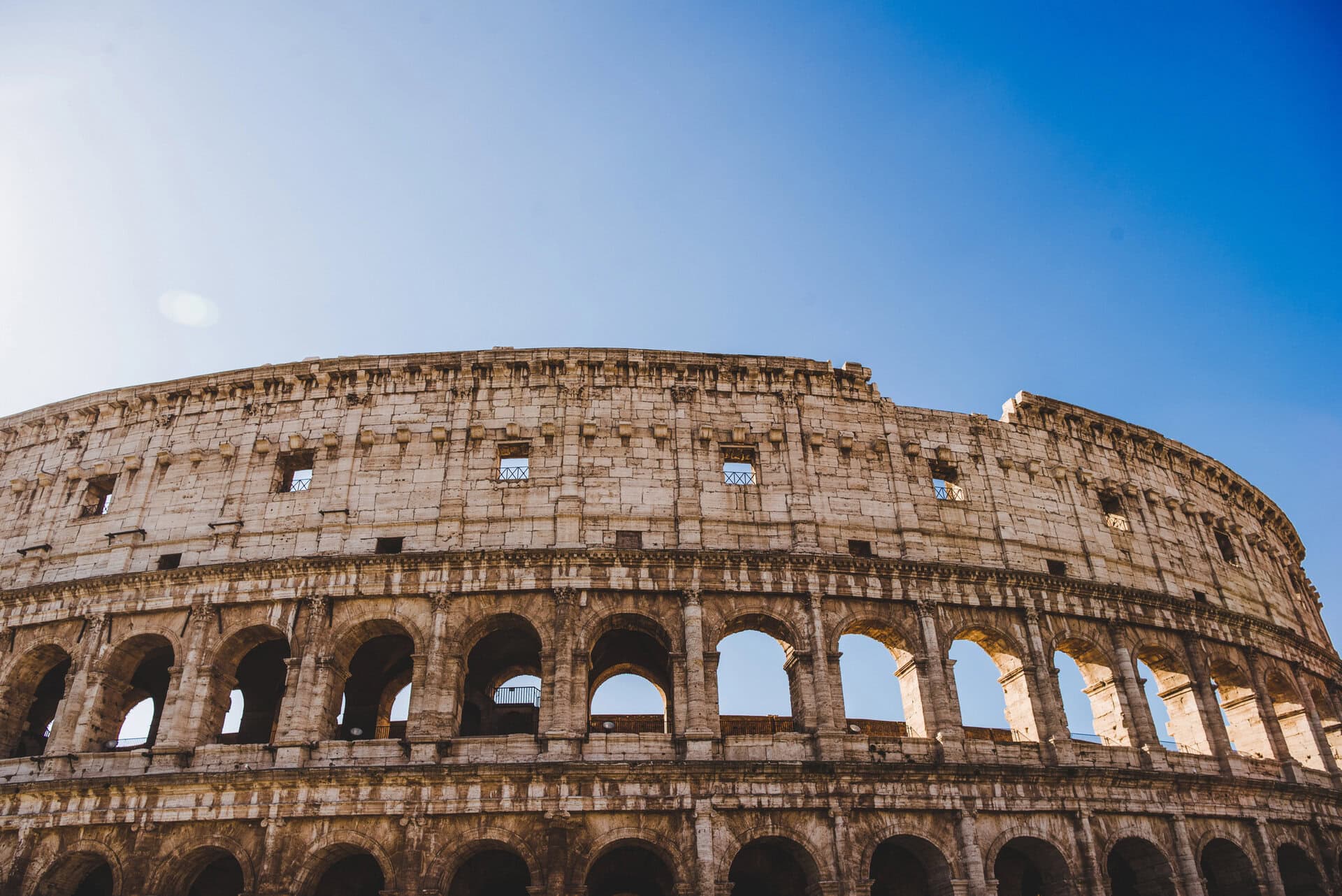 A stunning image capturing the grandeur of the Colosseum in Rome, featuring its iconic arches and ancient stonework against a vibrant blue sky.