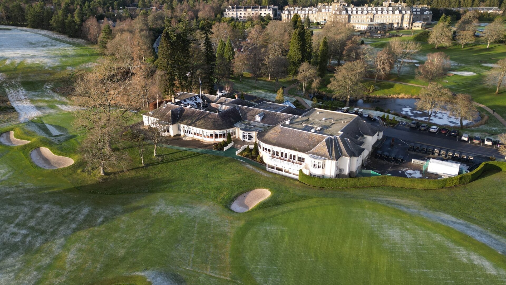 An aerial view of a Gleneagles Golf Course with a hotel in the middle surrounded with trees