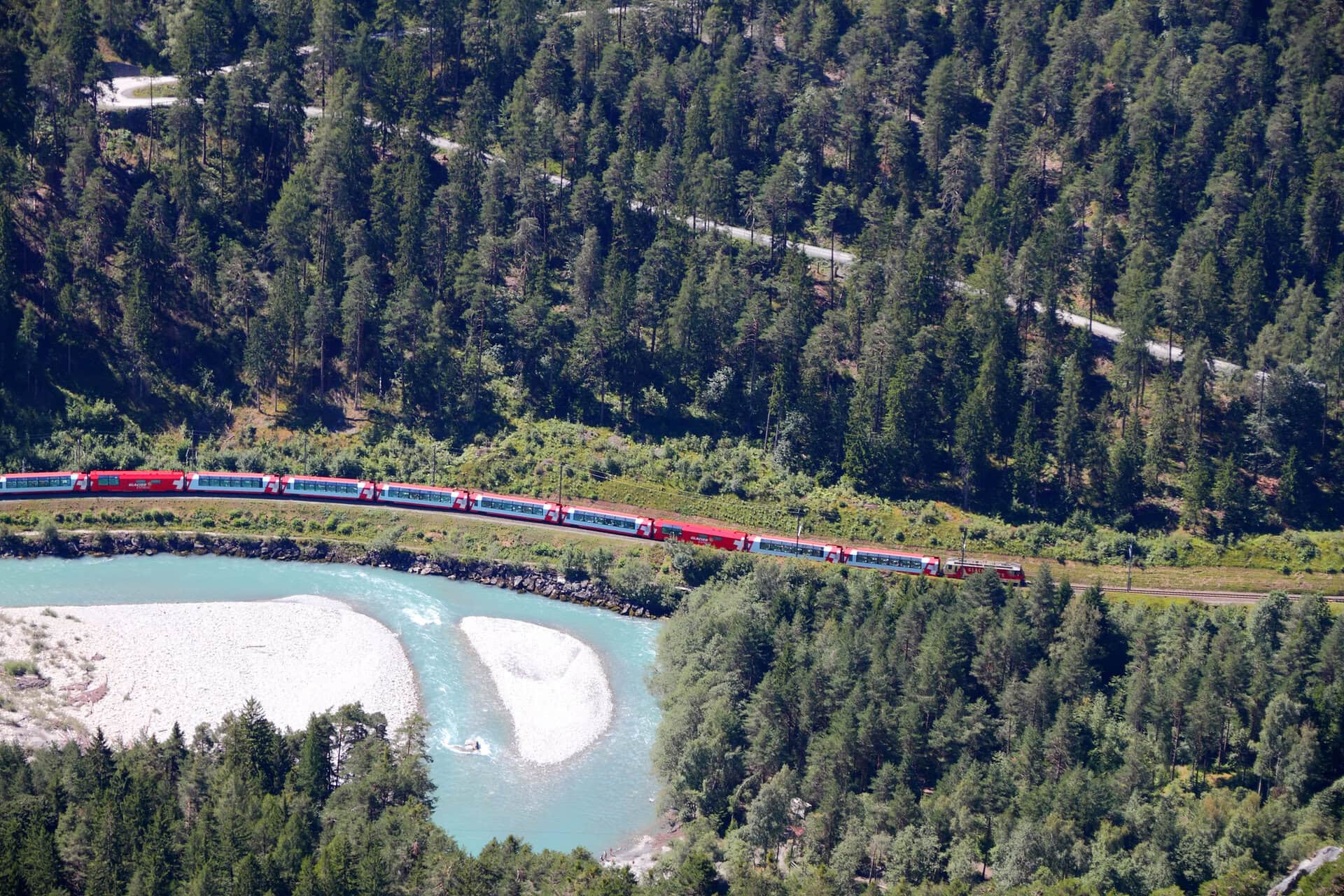 Train Glacier Express drives alongside river Rhine in canyon